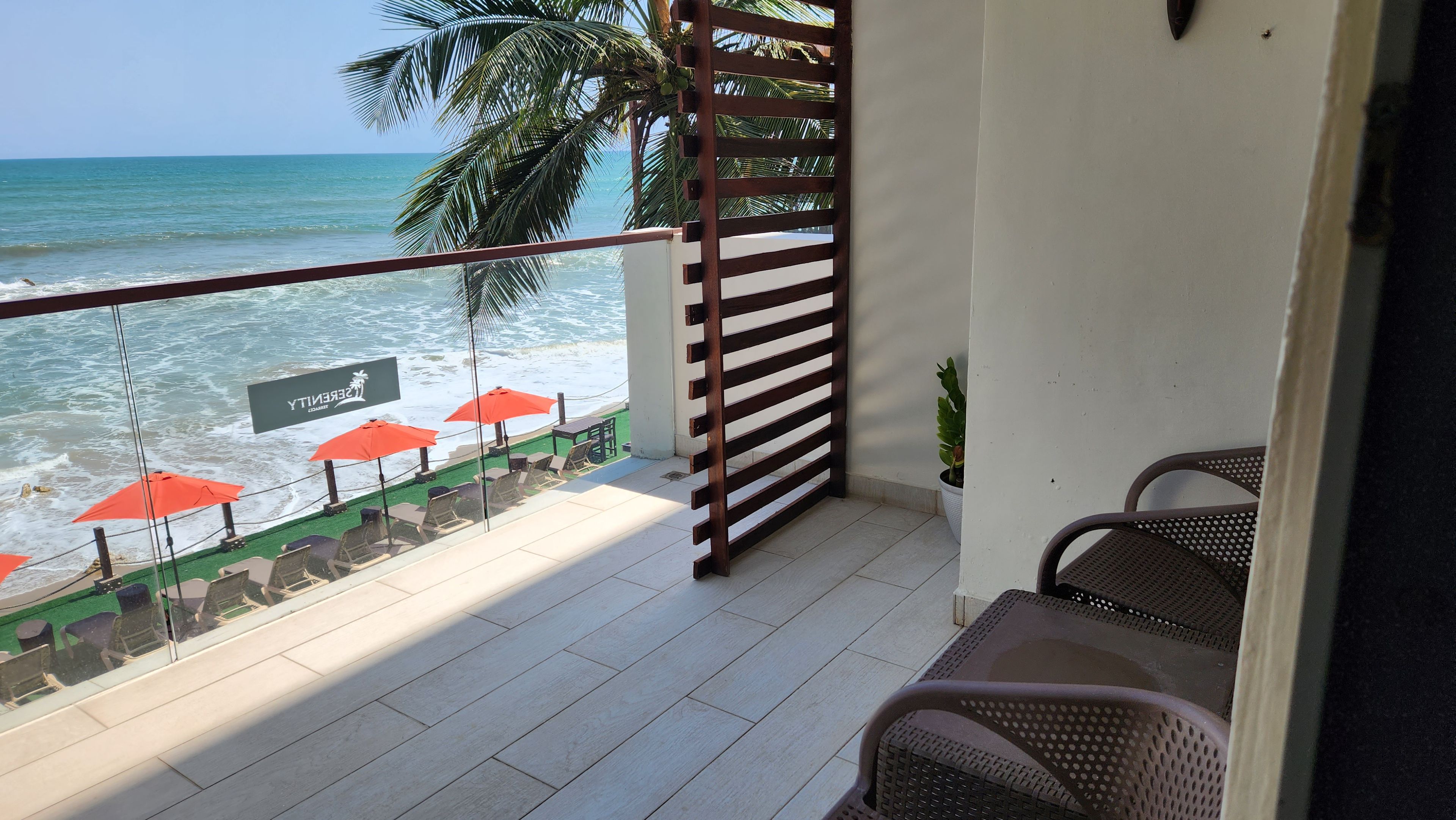 Un balcón con vista al océano, barandilla de listones de madera y un letrero que dice 'Serenity Beachside'.