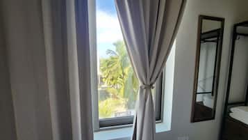 A room with a window, curtains, a mirror, and a towel rack.