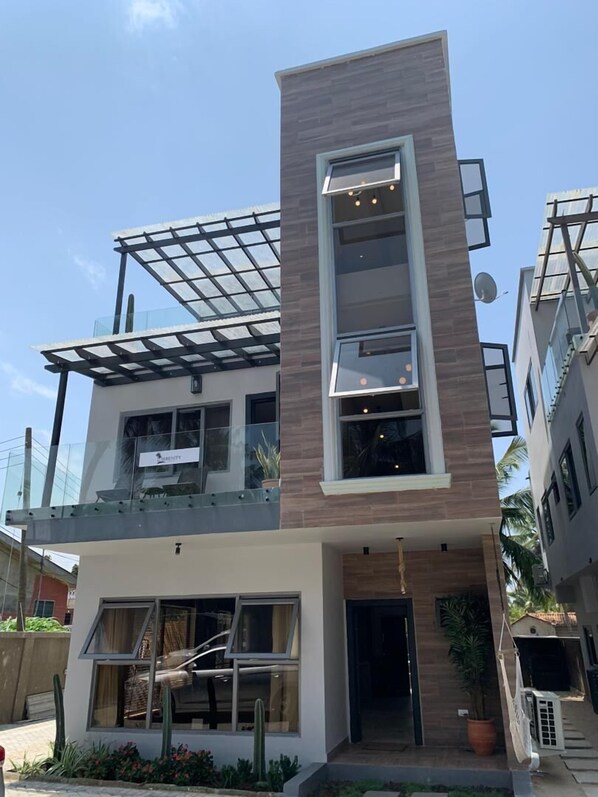 A modern two-story building with a glass balcony, a flat roof, and a satellite dish. - Serenity Residences & Spa - Kokrobite (Kokrobite)