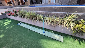 A miniature golf course with a putting green, a blue flagstick, and a scorecard.