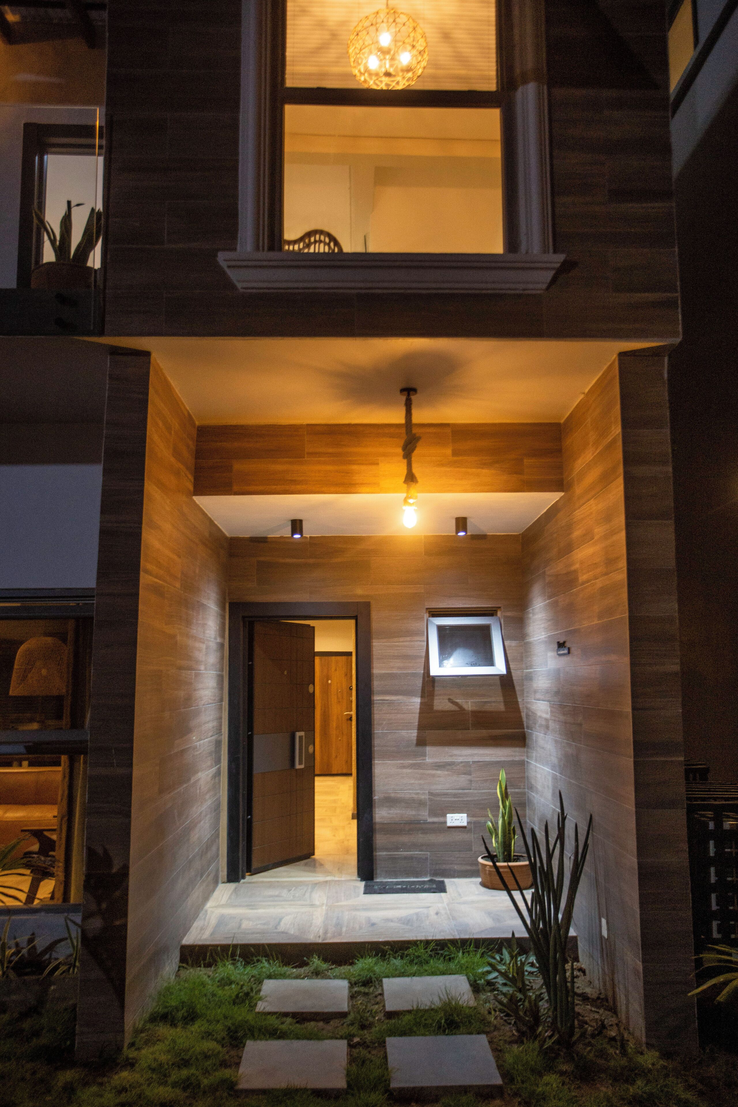 Un edificio moderno con fachada de madera, un balcón y una ventana pequeña.