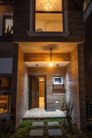 A modern building with a wooden facade, a balcony, and a small window. - Serenity Residences & Spa - Kokrobite (Kokrobite)