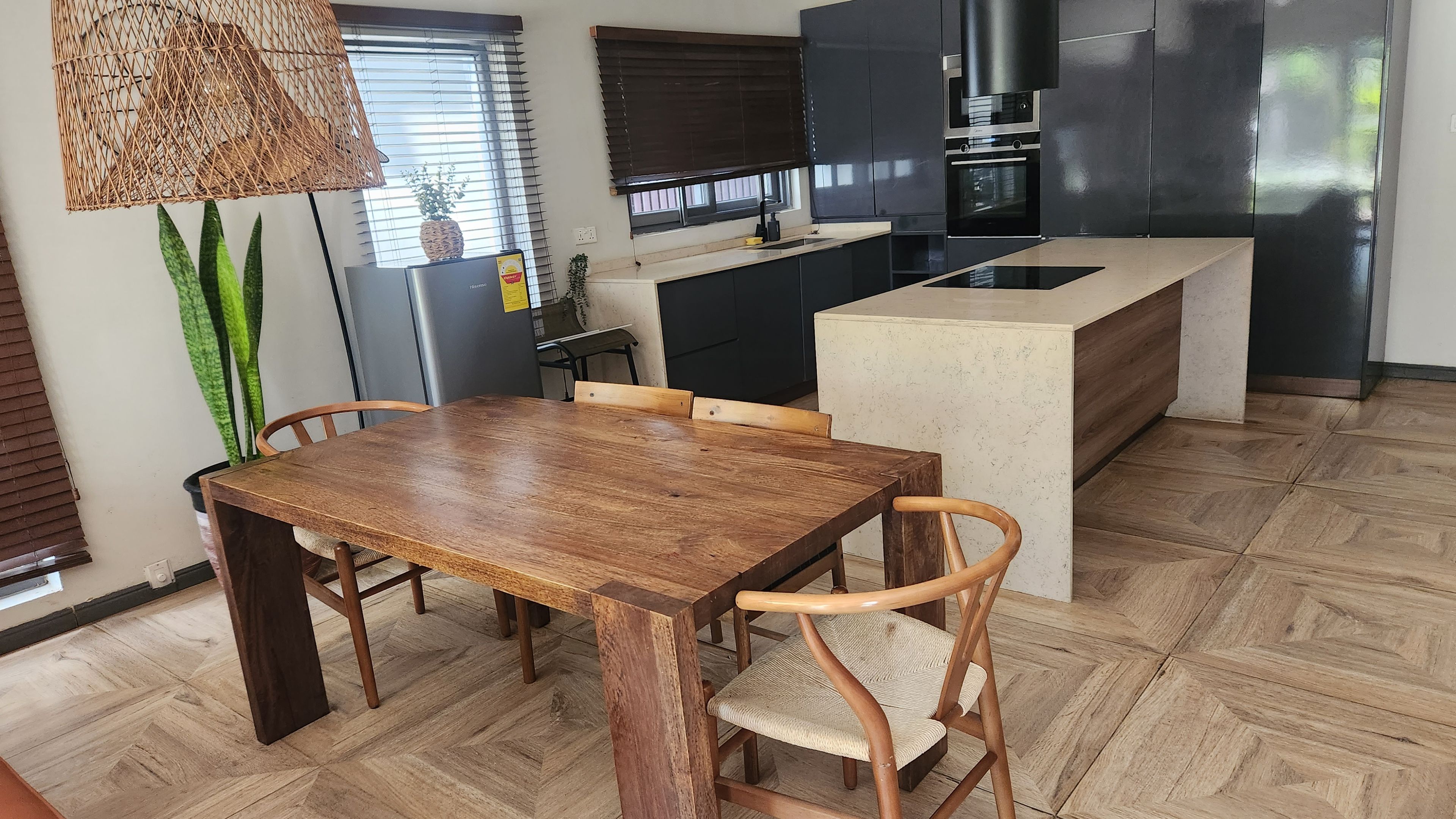 A modern kitchen with a wooden dining table, chairs, and a built-in island.