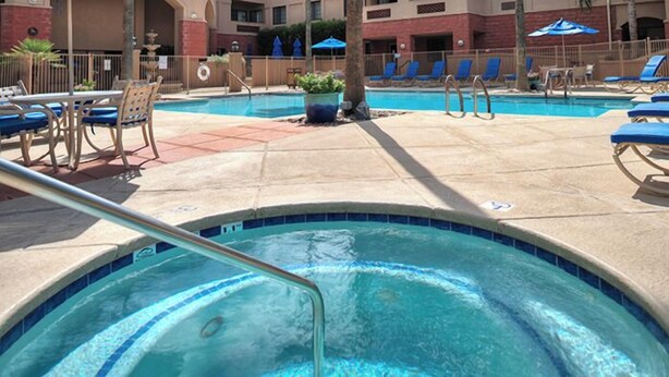 A pool area with lounge chairs, a hot tub, and a fenced poolside area.