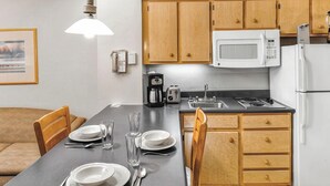A modern kitchen with wooden cabinets, a microwave, a coffee maker, and a dining table set for four.