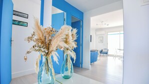 A modern interior with a blue accent wall, two glass vases with dried flowers, and a view into a dining area with a blue chair and table. - L'Horizon - 3 ch climatisé avec vue mer incroyable (Marseille)