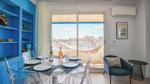 A dining area with a balcony view, a blue shelving unit, and a black round table. - L'Horizon - 3 ch climatisé avec vue mer incroyable (Marseille)