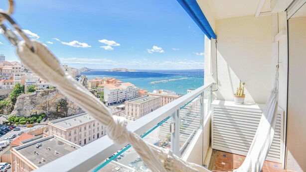 A balcony with a view of a coastal cityscape, including buildings and a body of water. - L'Horizon - 3 ch climatisé avec vue mer incroyable (Marseille)