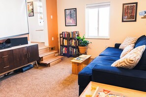 Relax in this cozy living space with a sofa, coffee table, bookshelf, and flat-screen TV.
