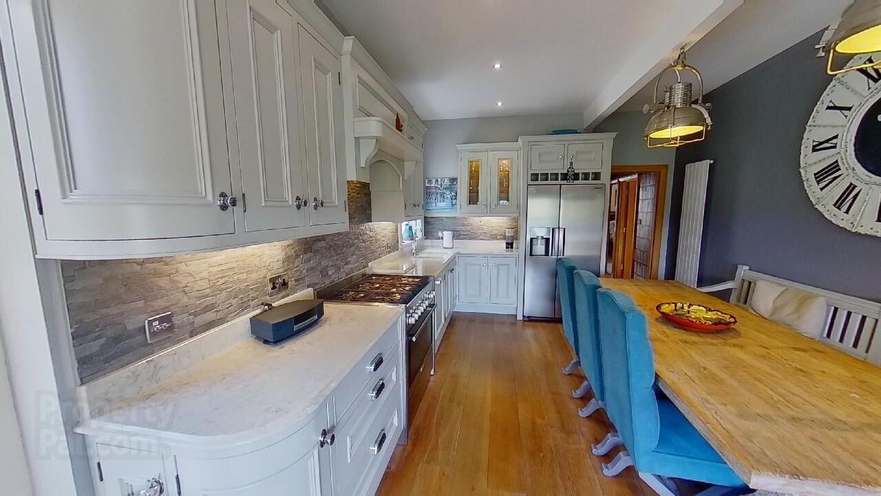 Una cocina moderna con armarios blancos, encimera de madera y comedor con sillas azules.