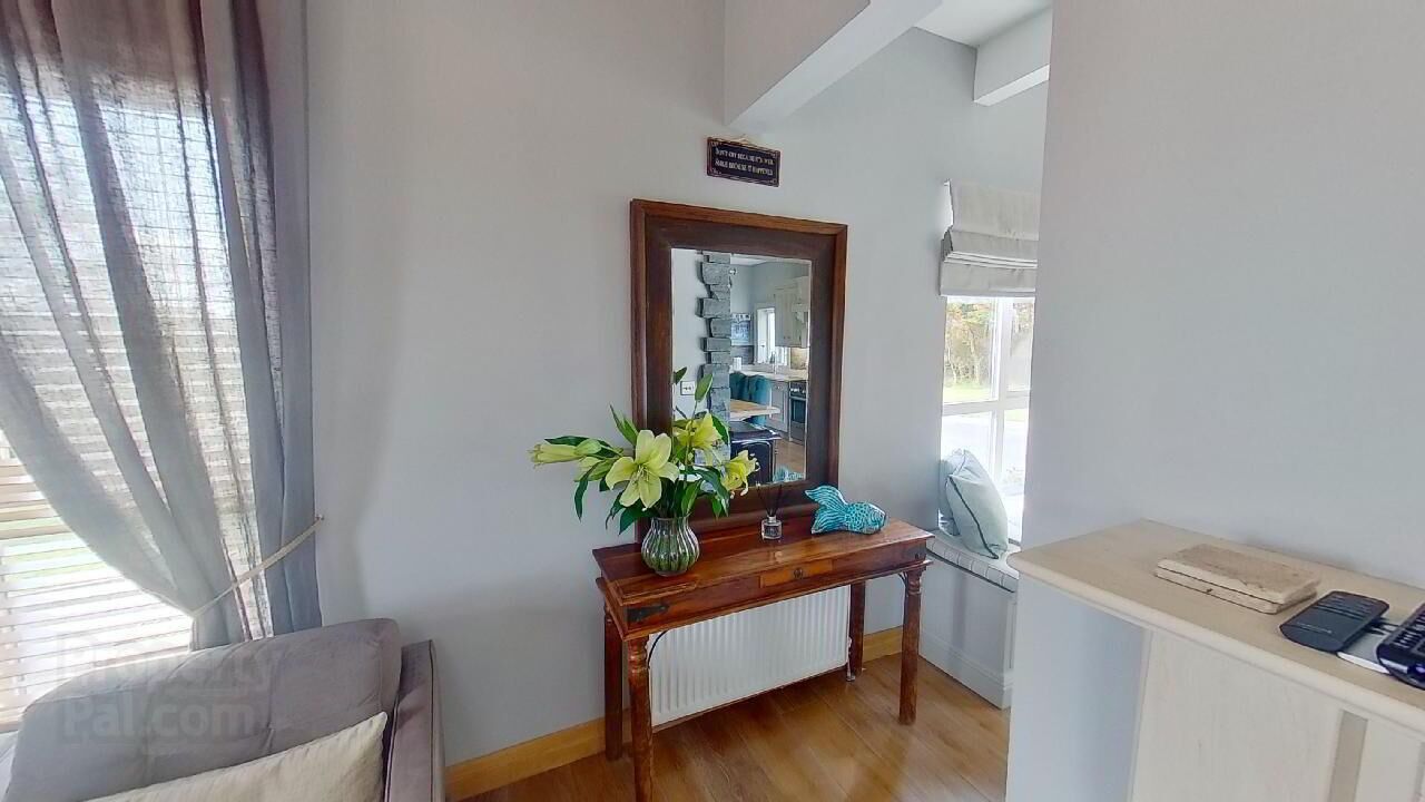 Een kamer met een houten console tafel, een spiegel, een bloemenvaas en een raam met blinds.