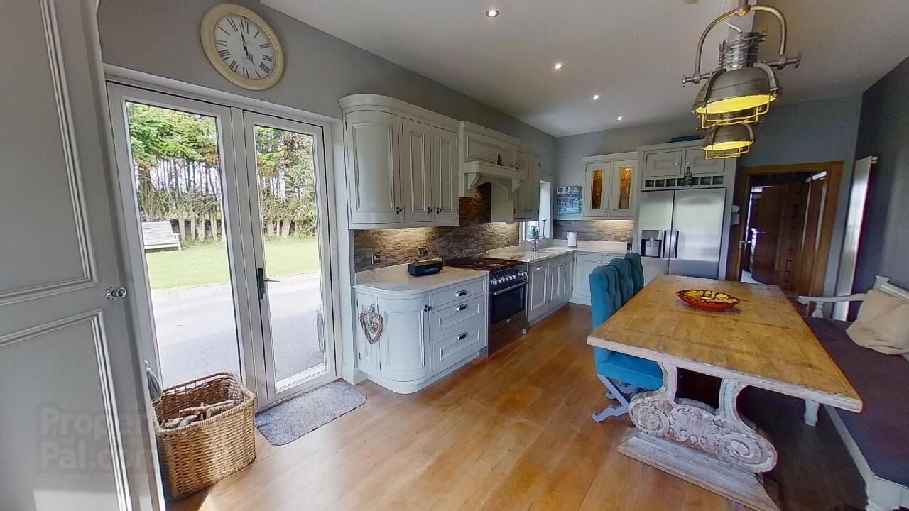 Una cocina amplia con armarios blancos, una mesa de comedor de madera y un horno empotrado.