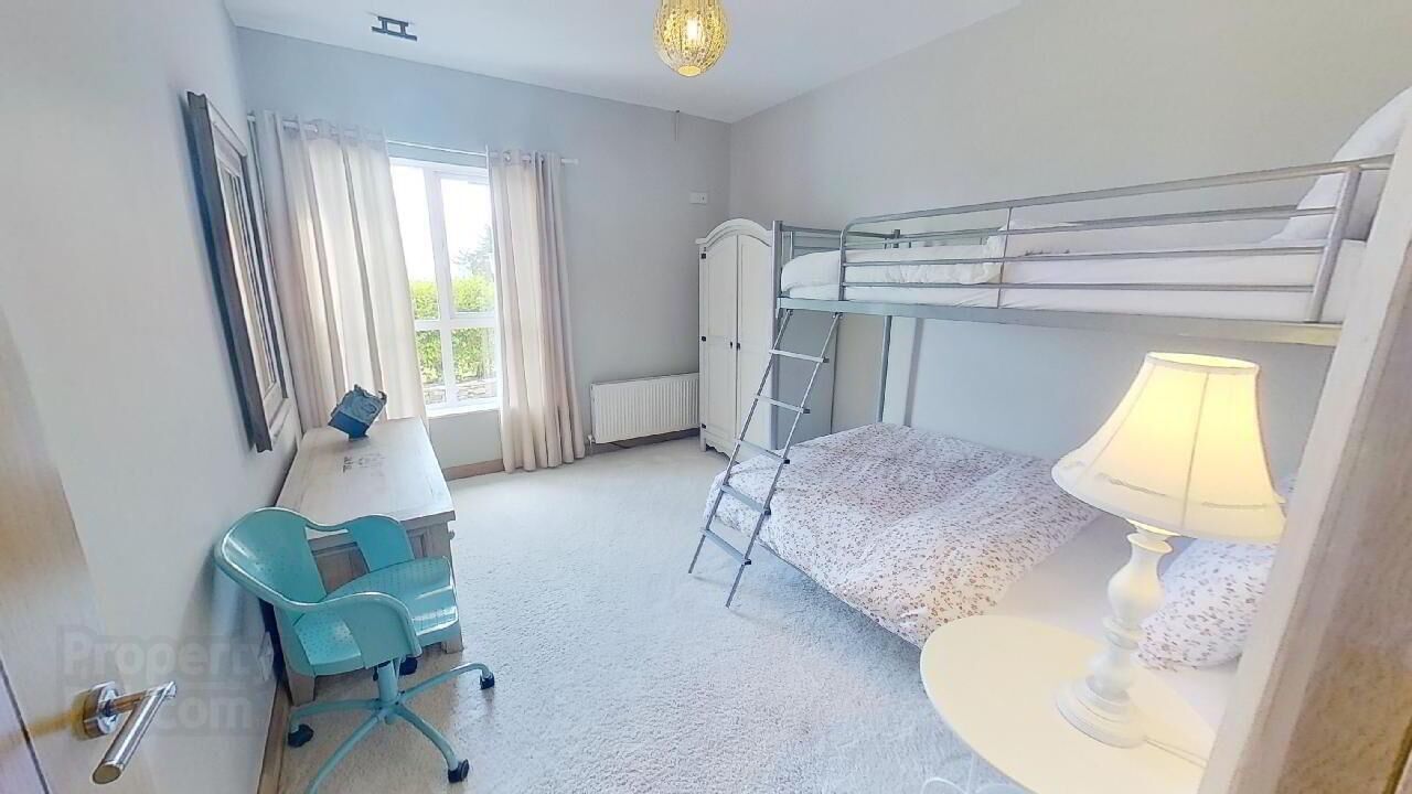 A bedroom with bunk beds, a desk, a chair, a lamp, and a wardrobe.