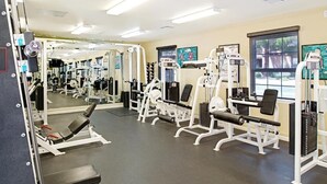 A gym with various exercise machines, mirrors, and a window.