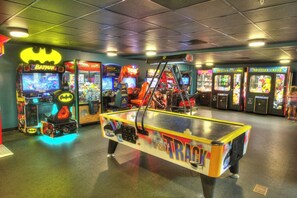 Een overdekte speelhal met diverse spelautomaten, waaronder een themamachine van Batman en een tafeltennistafel.