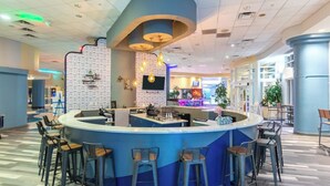 Eine moderne Bar mit einer gebogenen Theke, Barhocker und einer Wand mit Muster.