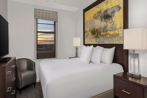 Une chambre d’hôtel avec un grand lit, une chaise, un bureau et une télévision.