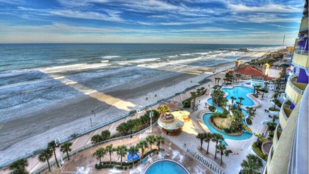 Ein Resort mit Blick auf den Strand, einem Poolbereich und einer Strandpromenade.