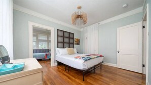 Een slaapkamer met een bed, een kaptafel, een spiegel, een deur en een raam.