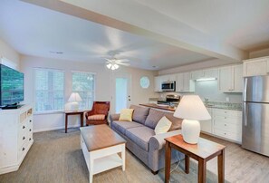 Ein Wohnzimmer mit einer Couch, einem Couchtisch, einem Fernseher und einem Deckenventilator.