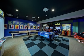 Ein Raum mit Billardtisch, Spielautomaten und einer blauen Wand mit dem Schriftzug 'BEACHHOODS'.