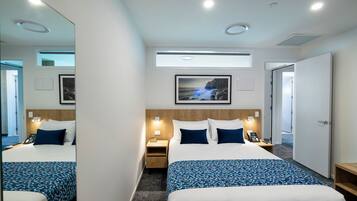 A hotel room with a large bed, bedside tables, a mirror, a picture on the wall, and a door.