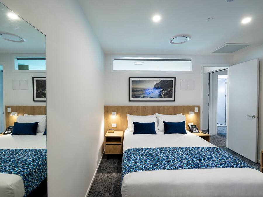 A hotel room with a large bed, bedside tables, a mirror, a picture on the wall, and a door.