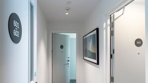 A hallway with a door labeled 601 and 602, a framed picture on the wall, and a carpeted floor. - Quest on Cambridge  (Christchurch)