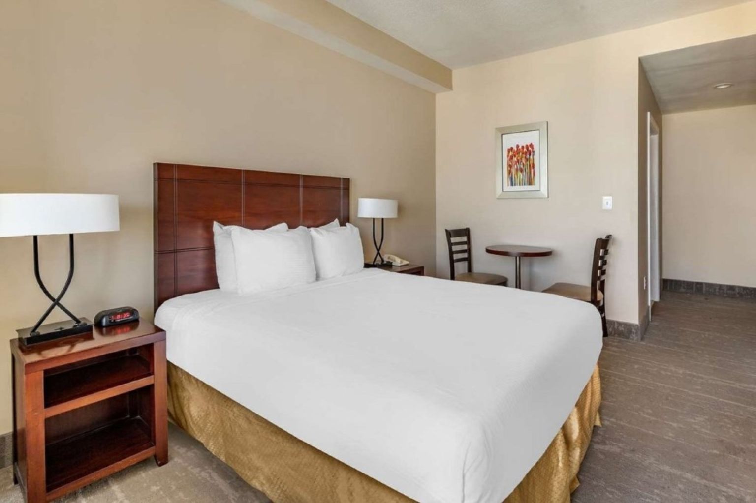 Habitación de hotel con una cama grande, mesitas de noche, un escritorio y una silla.