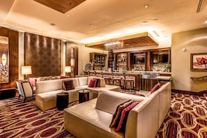 A hotel lobby with a bar area, seating arrangements, and a patterned carpet. - Virginia Beach | Oceanfront Escape | Resort Pool & Beach (Virginia Beach)