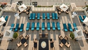 Vue aérienne d’un hôtel situé en bord de mer, avec une piscine, des chaises longues et une vue sur l’océan.