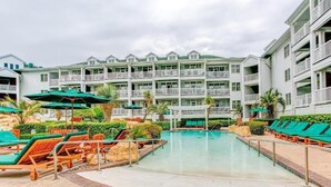 Et hotel med poolområde, flere balkoner og udendørs siddepladser.