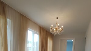 A spacious room with large windows, a chandelier, and a wooden floor.