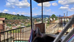 A balcony with a view of a town, a hammock, and a metal structure.