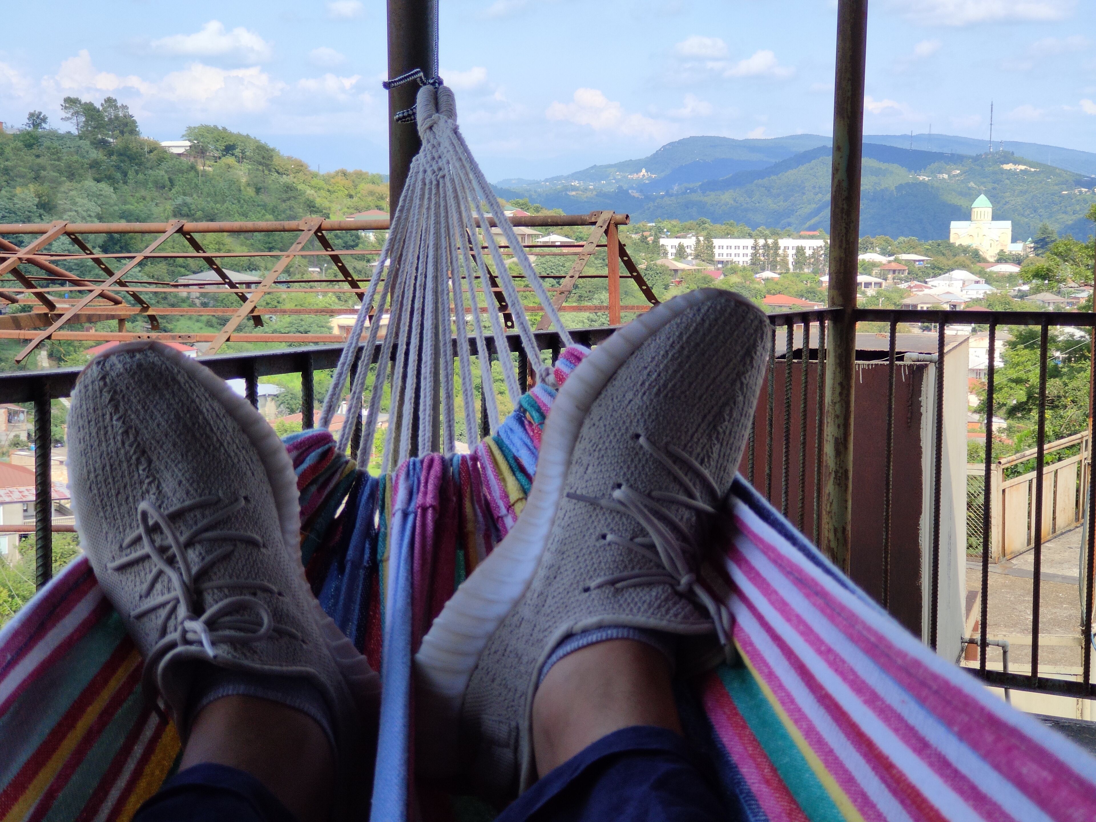 A hammock with a view of a mountainous landscape and a building with a green dome.