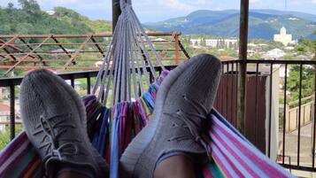 A hammock with a view of a mountainous landscape and a building with a green dome.