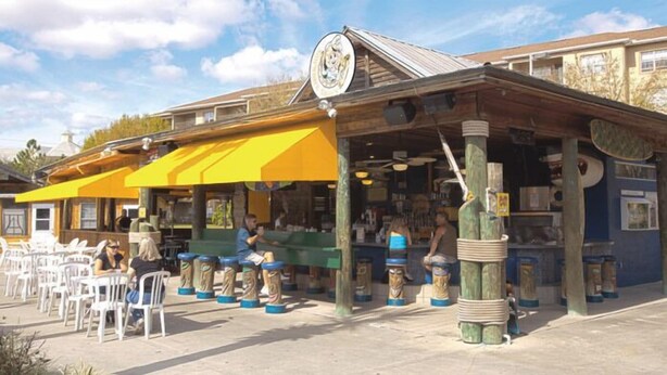 A restaurant with outdoor seating, a yellow awning, and a wooden facade.