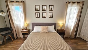 Une chambre à coucher avec un grand lit, deux tables de chevet, une chaise et un mur orné de tableaux.