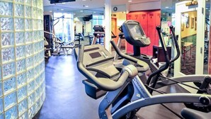 Un gimnasio con equipamiento de ejercicio, una pared de azulejos y una puerta roja al fondo.