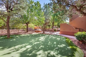 A courtyard with a green lawn, trees, and a building with a modern design.