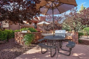 Un patio al aire libre con una parrilla, una mesa redonda y dos sillas.