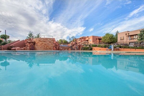 Una piscina con agua cristalina azul, rodeada de un paisaje rocoso y edificios.