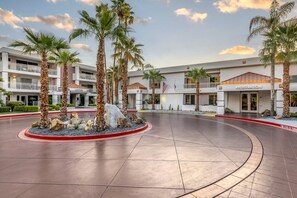 A hotel with a registration area, palm trees, and a paved courtyard.