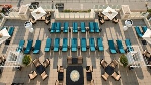 Luftaufnahme eines Hotels direkt am Strand mit Poolbereich, Liegestühlen und Blick auf den Ozean.