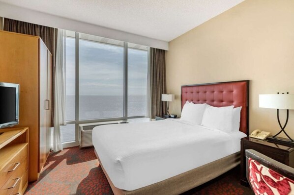 Una habitación de hotel con una cama grande, televisión, escritorio y vista al mar.