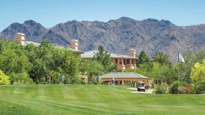 Un parcours de golf doté d’un club-house et offrant une vue sur les montagnes en arrière-plan.