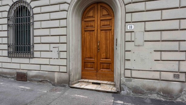 Un bâtiment doté d’une grande porte double en bois, d’une fenêtre avec des barreaux en métal et d’une petite enseigne portant le numéro « 11 ».