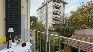 Un balcon avec une table dressée pour deux personnes, une bouteille de vin et une rose rouge.