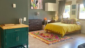 Quarto com cama, escrivaninha, cómoda e tapete colorido.