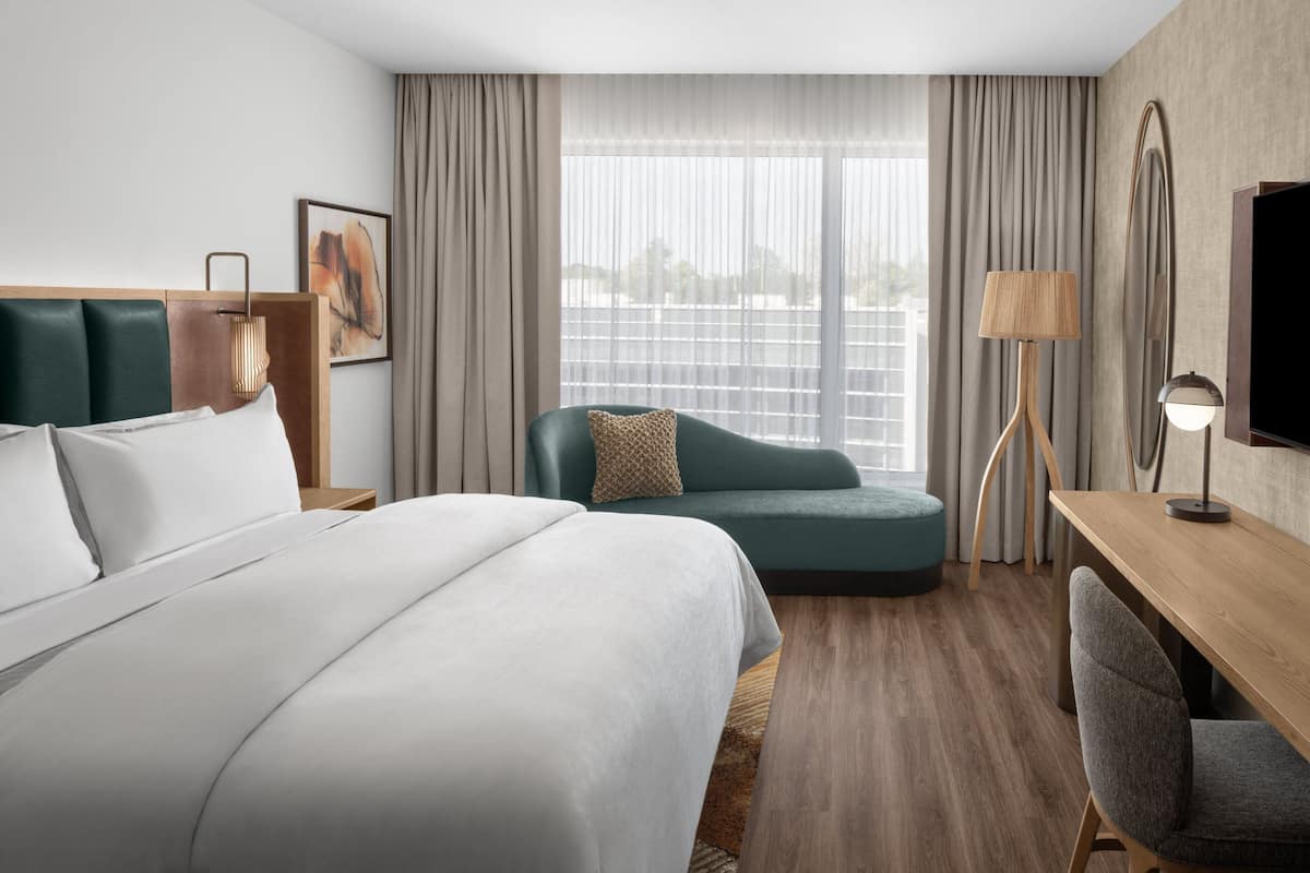 A hotel room with a large bed, a sofa, a desk, and a TV.